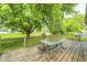 Wooden back deck features an outdoor dining area, perfect for enjoying the serene, tree-filled backyard at 5401 Padre Ln, Indianapolis, IN 46237