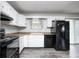 Compact kitchen featuring white cabinets, laminate countertops, and black appliances at 5401 Padre Ln, Indianapolis, IN 46237