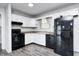 Compact kitchen featuring white cabinets, laminate countertops, and black appliances at 5401 Padre Ln, Indianapolis, IN 46237