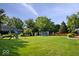 A large, manicured backyard with play equipment and mature trees creates a perfect Gathering space at 567 Hawthorne Dr, Carmel, IN 46033