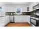 Well-lit kitchen featuring stainless steel appliances, ample counter space, and stylish wood flooring at 567 Hawthorne Dr, Carmel, IN 46033