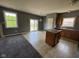 Spacious kitchen featuring an island, tile flooring, sliding glass doors to the backyard, and neutral gray walls at 5683 James Blair Dr, Indianapolis, IN 46234