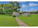 Backyard featuring two sheds, a concrete pathway, expansive lawn, and mature shade trees at 616 S Fuller Dr, Indianapolis, IN 46241