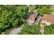 Aerial view of a brick home with a wooden deck, gravel driveway, and mature trees at 6477 N Park Ave, Indianapolis, IN 46220