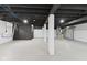 Finished basement area with painted floor, black ceiling with exposed joists, and white support pillars at 6477 N Park Ave, Indianapolis, IN 46220