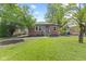 Quaint red brick home with a manicured lawn and lush trees in a suburban neighborhood at 6477 N Park Ave, Indianapolis, IN 46220