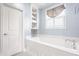 Bright bathroom featuring a soaking tub with a window view, built-in shelves, and a door at 6685 Chapel Xing, Zionsville, IN 46077
