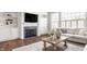 Cozy living room with a fireplace, built-in shelving, large windows, and hardwood floors at 6685 Chapel Xing, Zionsville, IN 46077