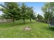 Large, well-manicured backyard with a fire pit and mature trees creating a serene outdoor space at 6927 Rose Tree Ct, Indianapolis, IN 46237