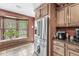 Bright kitchen showcasing stainless steel refrigerator, wood cabinets, and window overlooking yard at 7025 Chimney Rock Ct, Indianapolis, IN 46217