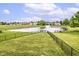 View of the neighborhood pond with a fountain, surrounded by lush green space and a black chain link fence at 7214 Morello Ln, Noblesville, IN 46062