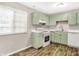 Bright kitchen with modern appliances, light green cabinets, and wood-style flooring at 8720 Yardley Ct # 108, Indianapolis, IN 46268