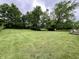 A wide shot of the green backyard of the property with mature trees, grass and a wooden deck at 902 N Bauman St, Indianapolis, IN 46214