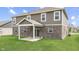 View of the home's backyard with a covered patio, green grass, and a partial brick exterior at 928 Ridge Rock Ln, Bargersville, IN 46106