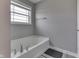 Modern soaking tub in a neutral toned bathroom with a window and fixtures at 928 Ridge Rock Ln, Bargersville, IN 46106