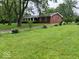 Quaint, red brick home featuring a lush green lawn and mature trees providing ample shade and curb appeal at 1101 E 25Th St, Muncie, IN 47302