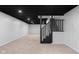 Basement with black ceiling, neutral carpet, and black railing stairs at 1127 Junco Dr, Columbus, IN 47203