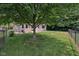 This backyard has a fenced-in yard, a large shade tree, and green grass at 1311 Old Hickory Dr, Greenwood, IN 46142