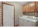 Laundry room features white appliances, overhead storage, and patterned wallpaper at 1311 Old Hickory Dr, Greenwood, IN 46142