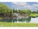 Scenic community pond featuring a tiered waterfall, lush landscaping and mature trees at 15937 Marsala Dr, Fishers, IN 46037