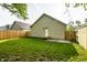 View of the backyard including grass, new wooden fence, garage, and back door entrance at 3818 Fetlock Dr, Indianapolis, IN 46227