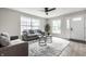 Bright living room featuring neutral walls, modern furniture, large windows, ceiling fan, and stylish decor at 3818 Fetlock Dr, Indianapolis, IN 46227