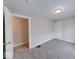 A well-lit bedroom with neutral walls, gray carpet, and an open door to the hallway at 418 Eastern Ave, Indianapolis, IN 46201