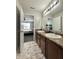 Bright bathroom featuring double sinks, modern lighting, and a view into the bedroom with a plush rug at 4925 Chip Shot Ln, Indianapolis, IN 46235