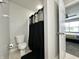 Clean bathroom featuring a toilet, decorative black shower curtain, and a glimpse into the bedroom at 4925 Chip Shot Ln, Indianapolis, IN 46235