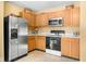 Efficient kitchen space with stainless steel refrigerator, microwave, updated cabinets, and smooth countertops at 5631 N Peppereel Way, McCordsville, IN 46055