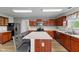 Kitchen with wood cabinets, stainless appliances, breakfast bar, and a laminate wood floor at 5637 Woodland Trace Blvd, Indianapolis, IN 46237