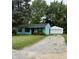 Charming blue home with a gravel driveway and detached two-car garage nestled amongst mature trees at 5938 Price Ln, Indianapolis, IN 46254