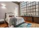 Bright bedroom with a large window, hardwood floors, exposed brick, and stylish decor at 611 N Park Ave # 104, Indianapolis, IN 46204