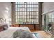 Bedroom featuring a large window, hardwood floors, exposed brick, and stylish decor at 611 N Park Ave # 104, Indianapolis, IN 46204