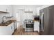 Modern kitchen featuring stainless steel appliances, white cabinets, and wood countertops at 614 N Drexel Ave, Indianapolis, IN 46201