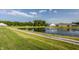Scenic community pond with a walking path, mature trees, fountain, and surrounding homes under a blue sky at 6350 Stallion Way, Indianapolis, IN 46260