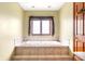 A relaxing bathtub with tile surround, a window, and a wood door at 7082 Hunters Ridge Dr, Plainfield, IN 46168