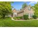 Charming brick home with manicured lawn, complemented by lush landscaping and blue shutters at 7818 Fawnwood Dr, Indianapolis, IN 46278