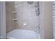 Shower and tub featuring a showerhead, tile surround, and built-in shelves at 11418 Geist Valley Dr, Indianapolis, IN 46236