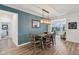 An open dining room with blue accent wall, rustic wood table and modern lighting fixture at 11429 Lottie Cir, Noblesville, IN 46060
