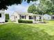 Single story home with green lawn, small bushes, covered entryway, and black shutters at 128 E 36Th St, Anderson, IN 46013