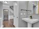 Stylish powder room with pedestal sink, gold mirror, and view of hallway at 13304 Landwood Dr, Fishers, IN 46037