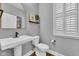 Well-lit powder room featuring a pedestal sink, toilet, window, and tasteful decor at 13304 Landwood Dr, Fishers, IN 46037