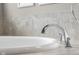 Close up of modern bathtub and chrome faucet surrounded by neutral tile at 1497 Maple Ridge Ct, Columbus, IN 47201