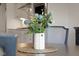 Close-up of a dining table flower arrangement, complemented by neutral tones and a glimpse of the kitchen in the background at 1497 Maple Ridge Ct, Columbus, IN 47201