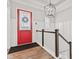 Bright foyer showcasing a red front door, staircase with white railings, and elegant lighting fixture at 1505 Avondale Dr, Westfield, IN 46074