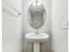 Bright white bathroom with a pedestal sink and a sleek, modern oval mirror at 1739 Wedgewood Pl, Avon, IN 46123