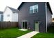 Backyard with freshly cut lawn and a dark gray home featuring a light green back door at 2014 W Michigan St, Indianapolis, IN 46222