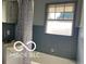 Bathroom featuring a tub/shower combo and grey-blue tile at 2028 Gilmore St, Columbus, IN 47201