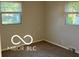 Comfortable bedroom with neutral paint, warm carpet, and natural light from two large windows at 2028 Gilmore St, Columbus, IN 47201